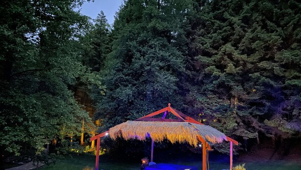 A gazebo with a thatched roof, a built-in barbecue, and a seating area with chairs and a table. - Inch Schoolhouse - Event Residence (Downpatrick)