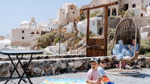 A beach setting with a wicker chair, a table, and a child playing.