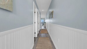 A hallway with white wainscoting, a wooden floor, and a light blue wall.