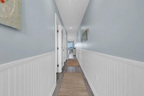 A hallway with white wainscoting, a wooden floor, and a light blue wall.