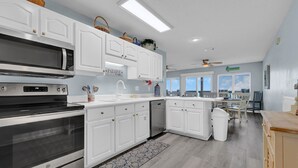 A modern kitchen with white cabinetry, stainless steel appliances, and a view to the outside.