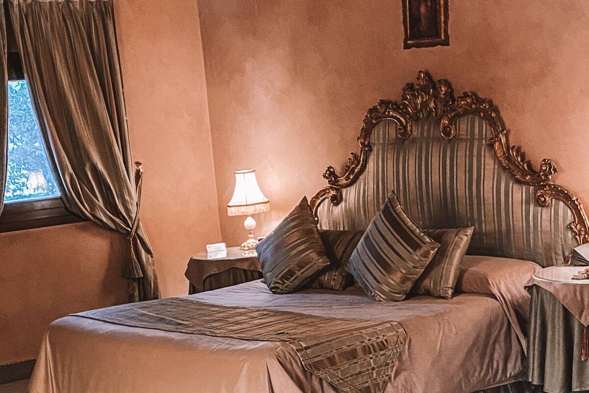 A hotel room with a large bed, two bedside tables, a round table, and a chair.