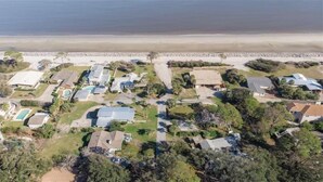 Vue aérienne d’une zone résidentielle côtière, avec des maisons, une plage et une côte rocheuse.