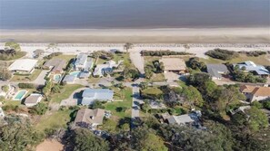 Vue aérienne d’une zone résidentielle côtière, avec des maisons, une plage et une côte rocheuse.
