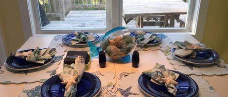 A dining table set with blue plates and napkins, a decorative glass bowl, and a candle.