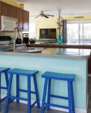 Une cuisine avec des meubles en bois, un ventilateur de plafond et une fenêtre donnant sur un beau paysage.