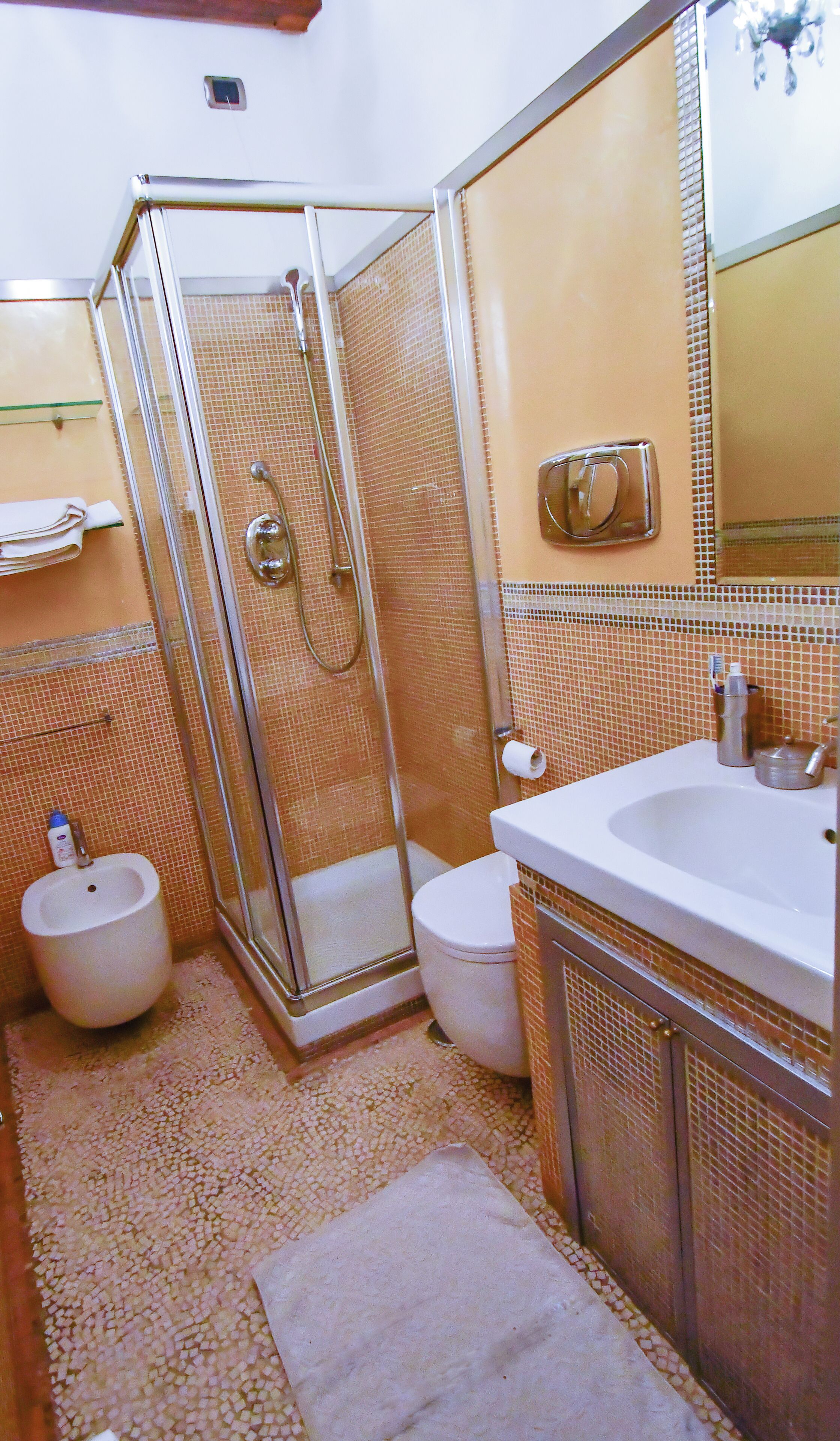 A bathroom with a glass-enclosed shower, a white sink, and a toilet.
