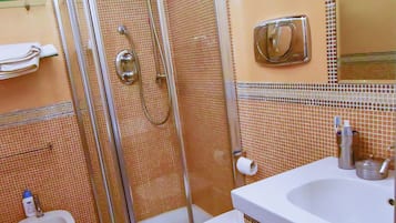 A bathroom with a glass-enclosed shower, a white sink, and a toilet.