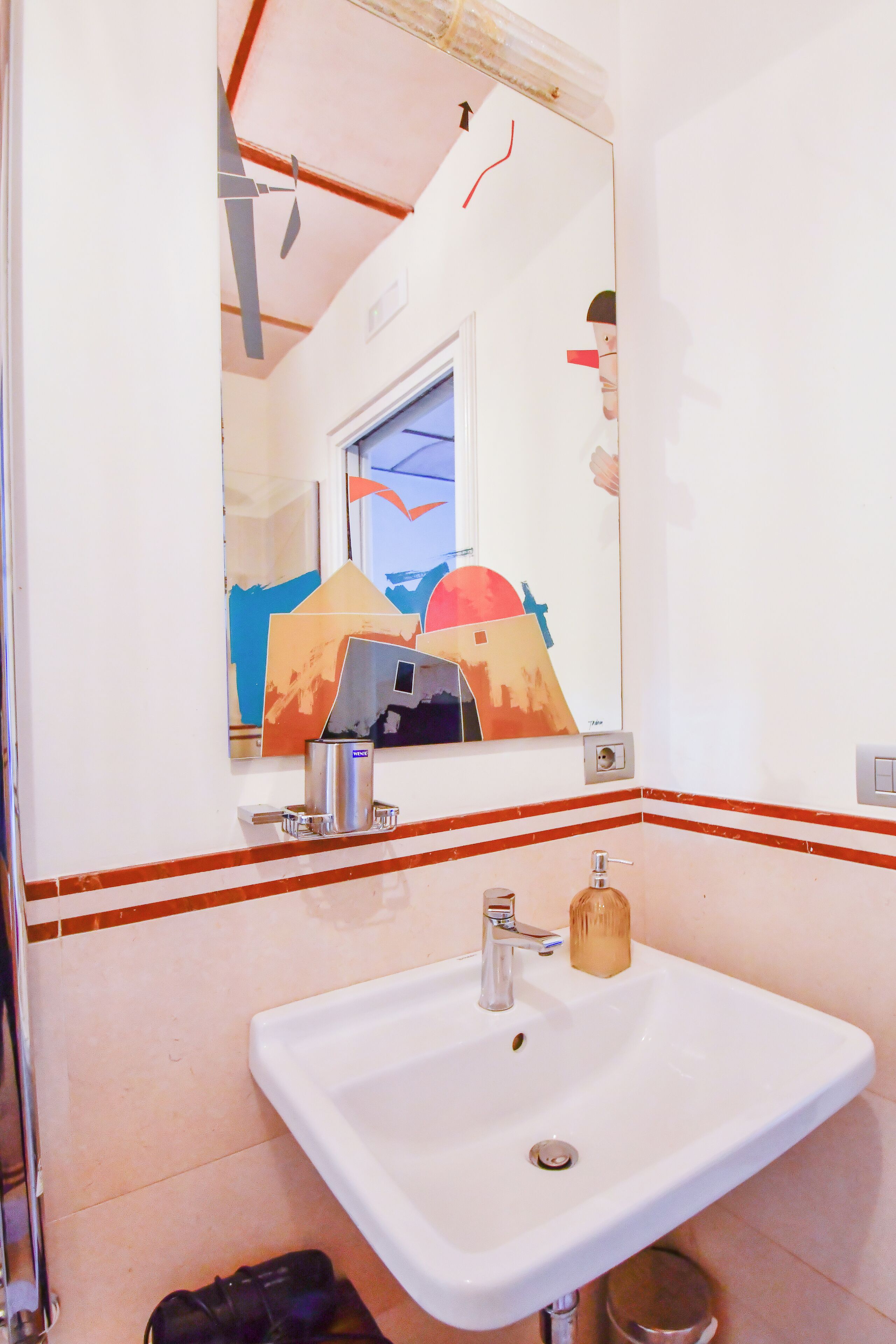 Un baño con lavamanos blanco, un espejo y una ventana con vistas a la montaña.