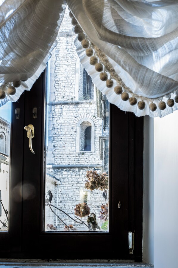 A view through a black door with a white curtain, revealing a stone building with a window and a door. - Guest House Al Convento (Potenza)