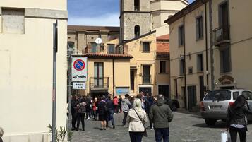Una calle empedrada con edificios históricos, una torre de campanas y una señal de 'no estacionar'.