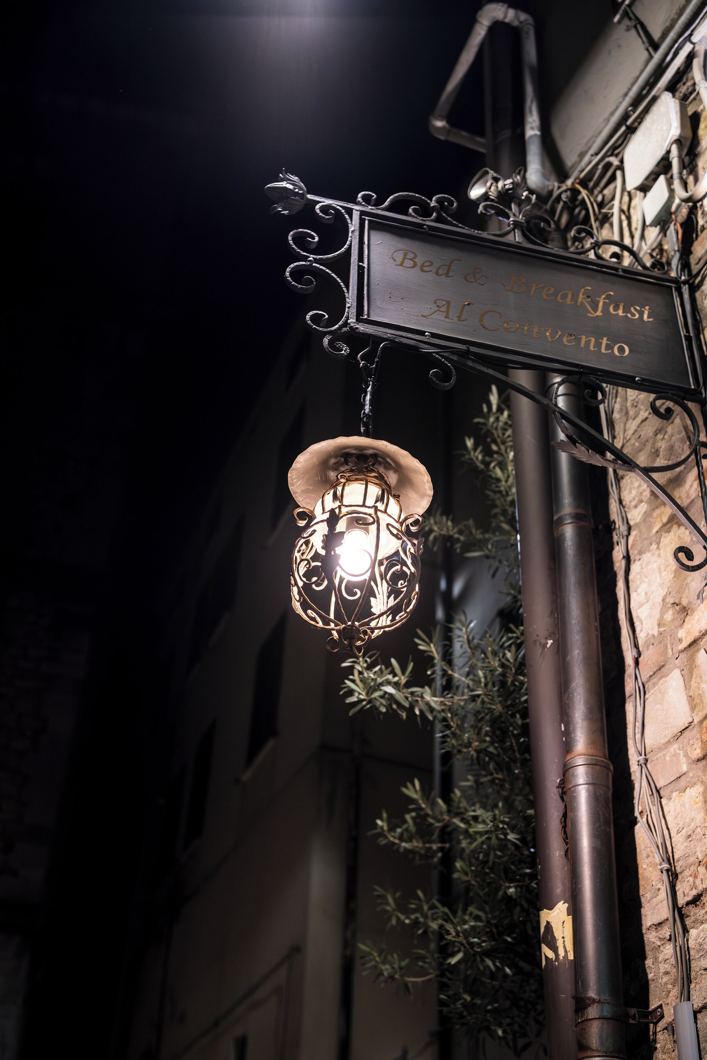A street sign for "Bed & Breakfast Al Convento" with a decorative lantern hanging below it.