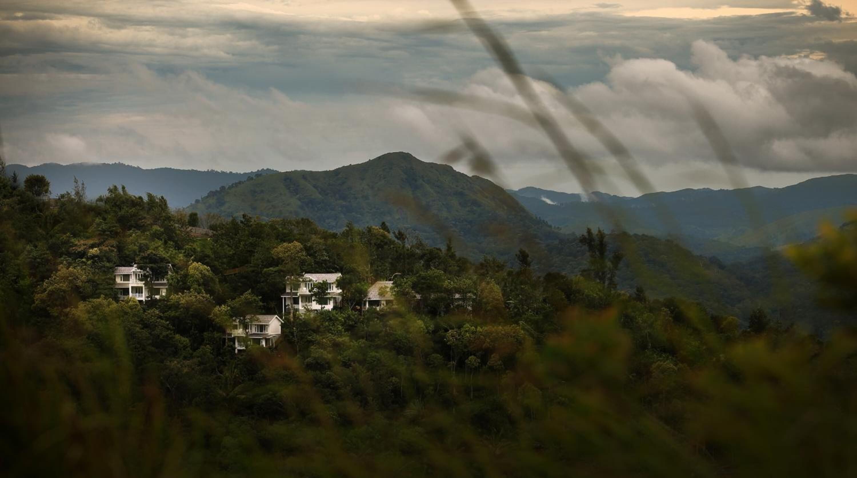 Un paisaje montañoso con varias edificaciones blancas ubicadas entre abundante vegetación.
