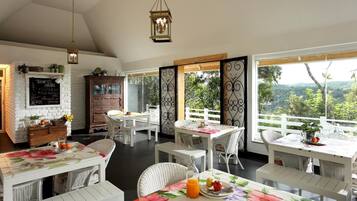 Un comedor con mobiliario de mimbre blanco, un armario de madera y un menú en una pizarra.