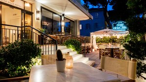 An outdoor dining area with tables and chairs, a staircase leading to the entrance, and a sign for Hotel de la Ville. - De La Ville Boutique Hotel (Cattolica)