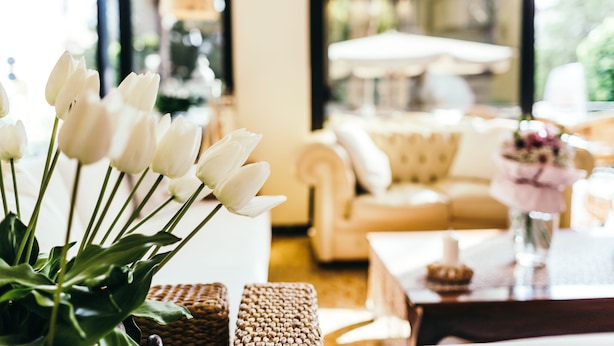 A room with a white sofa, a wicker basket, and a vase with white flowers. - De La Ville Boutique Hotel (Cattolica)