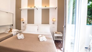 A hotel room with a bed, two bedside tables, a nightstand, a teddy bear, and a window with a view of greenery. - De La Ville Boutique Hotel (Cattolica)