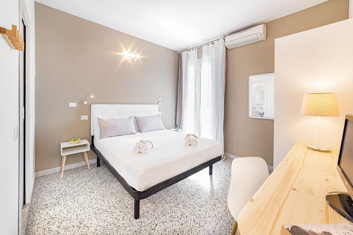 Une chambre à coucher comprenant un lit, un bureau, une chaise, une table de chevet et une lampe.