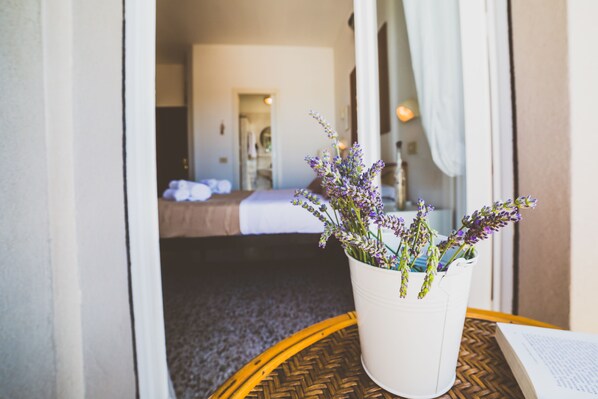 A hotel room with a bed, a potted lavender plant on a round table, and a doorway leading to another room. - De La Ville Boutique Hotel (Cattolica)