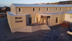 Un hotel con techo plano, una escalera que conduce a la entrada y un letrero que dice "Brae Hotel".
