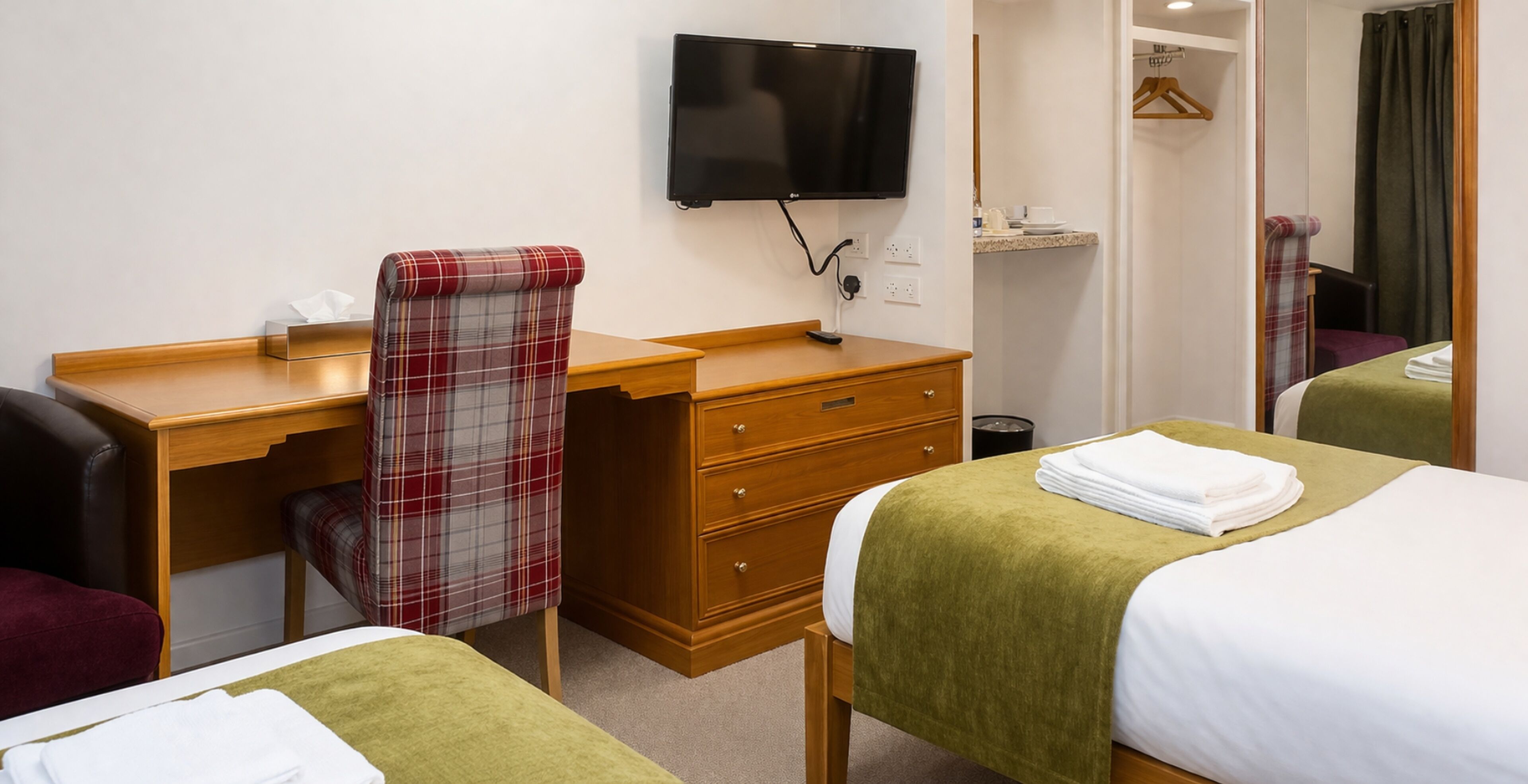 Une chambre d’hôtel équipée d’un lit, d’un bureau, d’une chaise, d’une télévision et d’un miroir.
