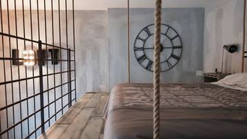 Ein Schlafzimmer mit einem Bett, einer Wanduhr, einem Seil und einem Metallgitter.