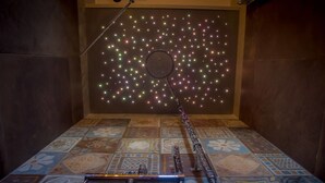 Una habitación con piso estampado, un narguilé y una pared decorada con luces multicolores.