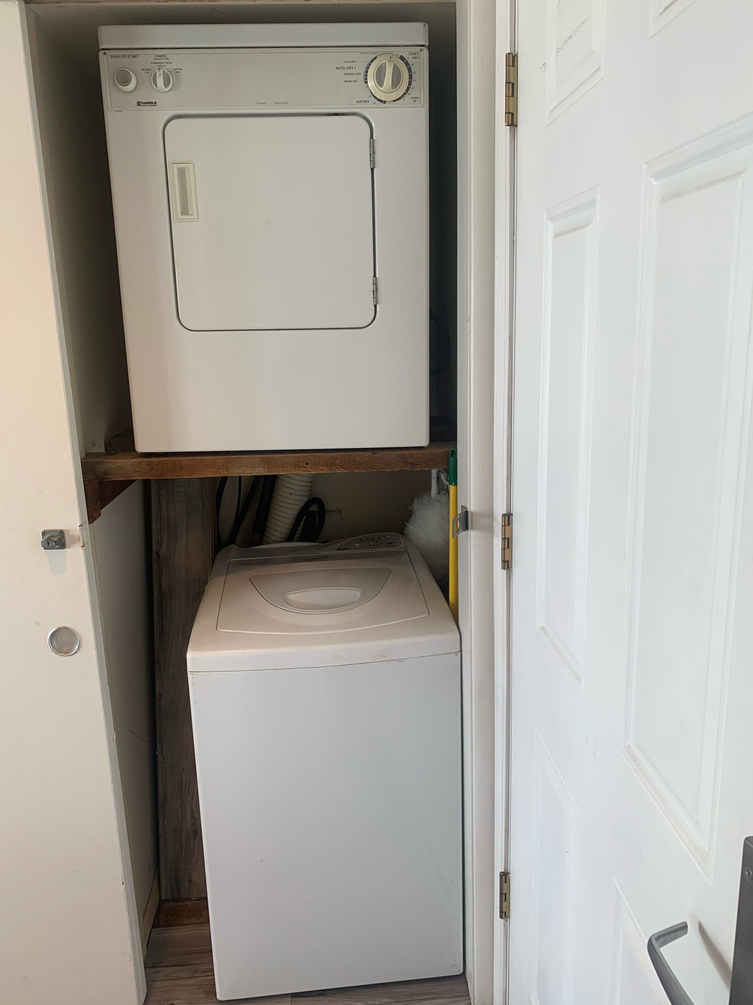 Une petite buanderie équipée d’un lave-linge à chargement par le haut et d’un sèche-linge à chargement frontal.