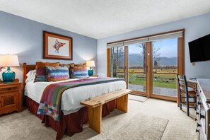 A bedroom with a bed, a bench, a desk, and a view of the outdoors. - RMR: Greyling 4511 Condo in The Aspens/Wilson,WY (Wilson)