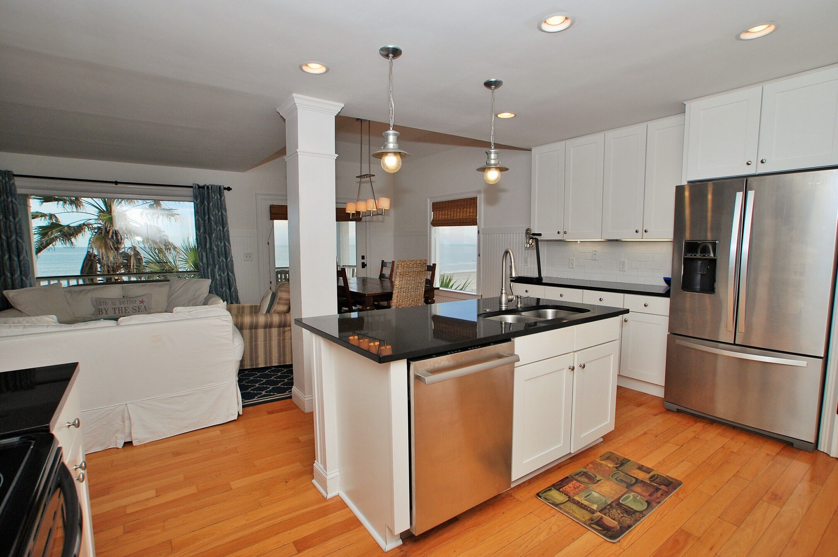 A modern kitchen with white cabinets, a stainless steel refrigerator, and a central island with a sink.