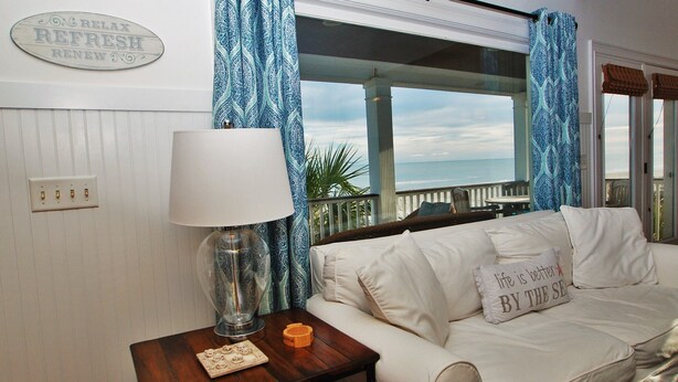 Una habitación acogedora con un sofá blanco, una lámpara y vistas al océano.