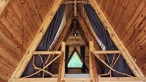 Un intérieur en bois avec un escalier central en bois menant à une mezzanine aménagée en espace nuit.