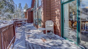 A wooden building with large glass doors and windows, a covered outdoor seating area with tables and chairs, and a snow-covered deck. - Waterdance 475a 5 Bedroom Townhouse by RedAwning (Frisco)
