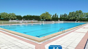 A swimming pool with a tiled deck, surrounded by trees and umbrellas. - GÎte Antonio for 6 people in Salamanca, with swimming pool and Wi-Fi connection /OFFERS (Vitigudino)