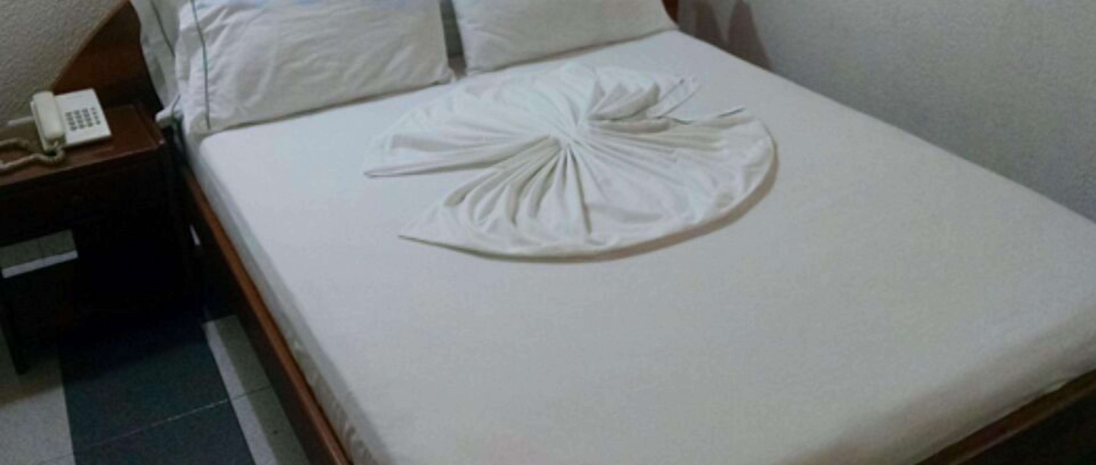 A bed with a white sheet and a decorative pillow.