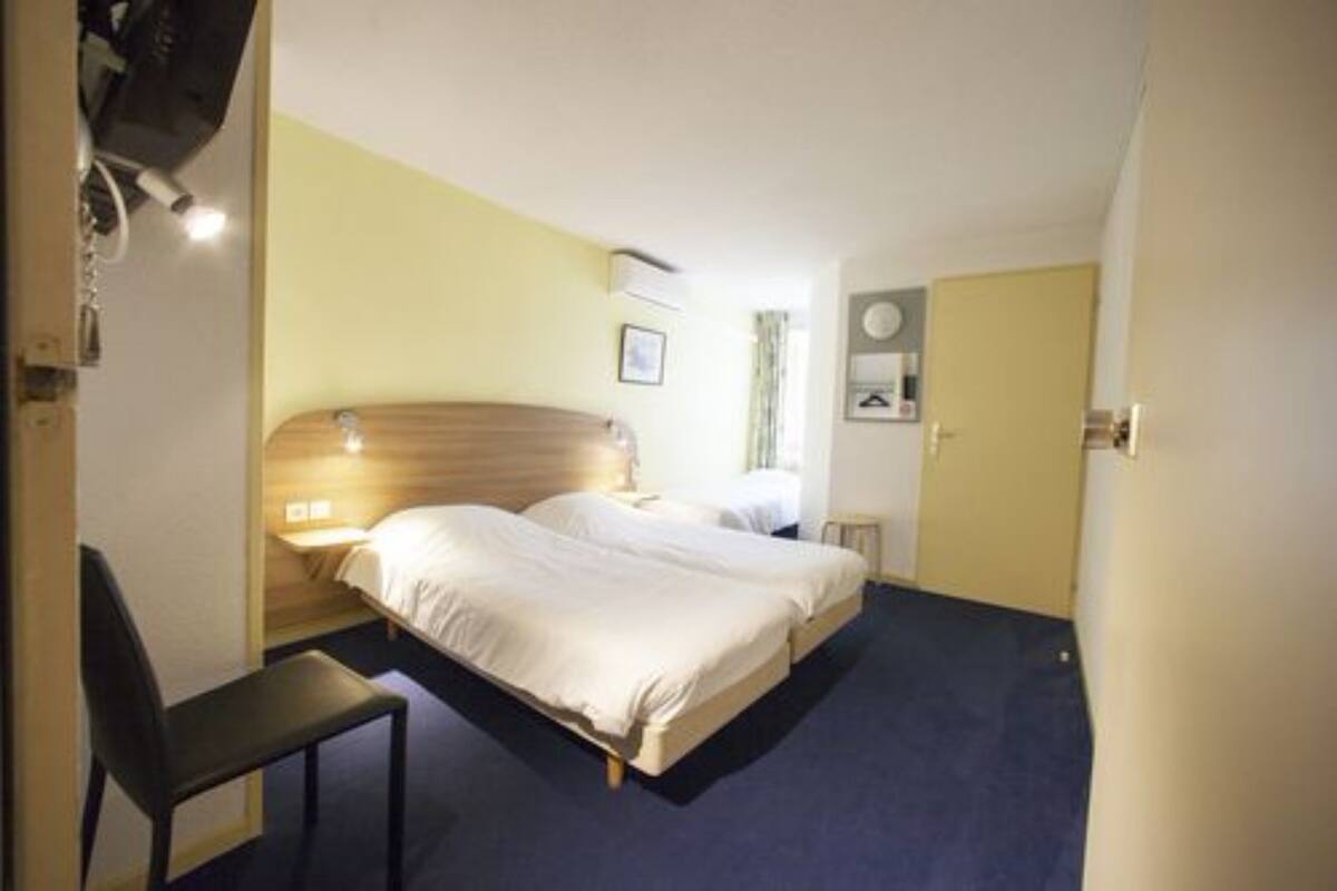 A hotel room with two beds, a desk, and a chair.