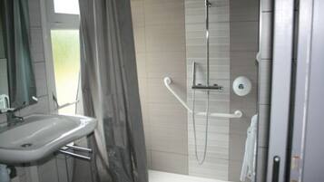 Ein Badezimmer mit Waschbecken, einer Dusche mit Duschbrause und einem Handtuchhalter.