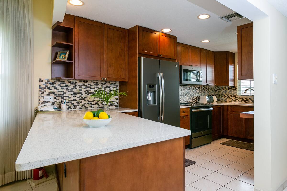 A modern kitchen with wooden cabinets, a stainless steel refrigerator, and a tiled backsplash.