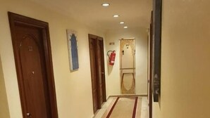 A hallway with wooden doors, a red carpet, and recessed ceiling lights. - Hotel Amouday (Casablanca)