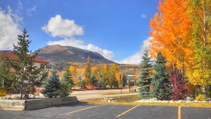 Un parking bordé d’arbres aux couleurs automnales, avec une montagne en arrière-plan.