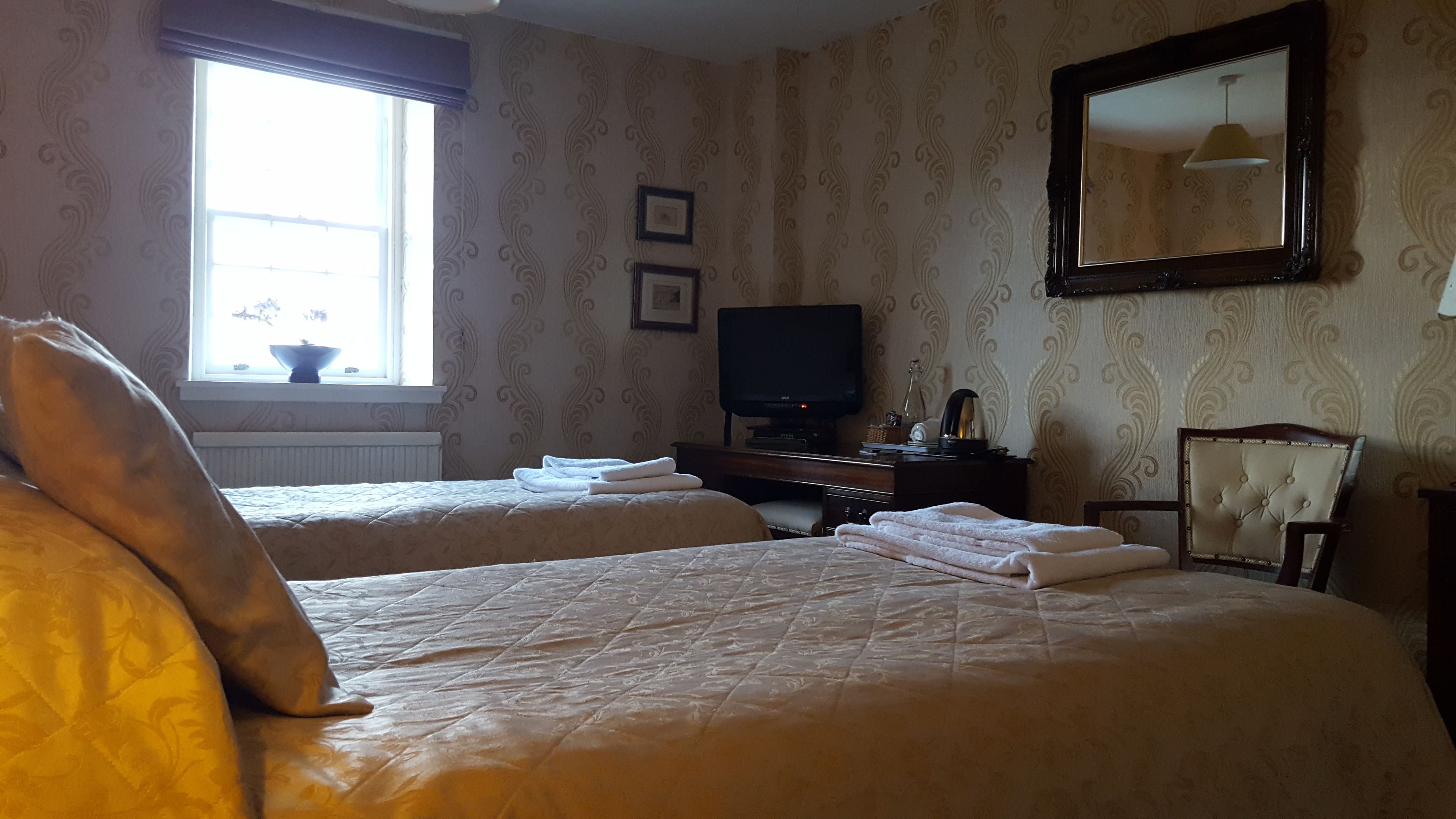 A hotel room with two beds, a television, a desk, and a chair.