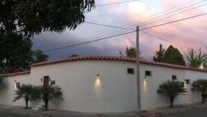 Un edificio de dos plantas con techo de tejas rojas y fachada blanca. Cuenta con ventanas pequeñas y una puerta en la planta baja, y un balcón en el segundo piso.