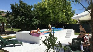 A pool area with a wooden deck, lounge chairs, and a small inflatable pool. - Bed & Breakfast Isonzo (Turriaco)