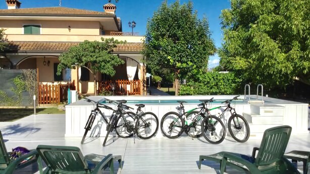 A poolside area with green chairs, bicycles, and a pool. - Bed & Breakfast Isonzo (Turriaco)
