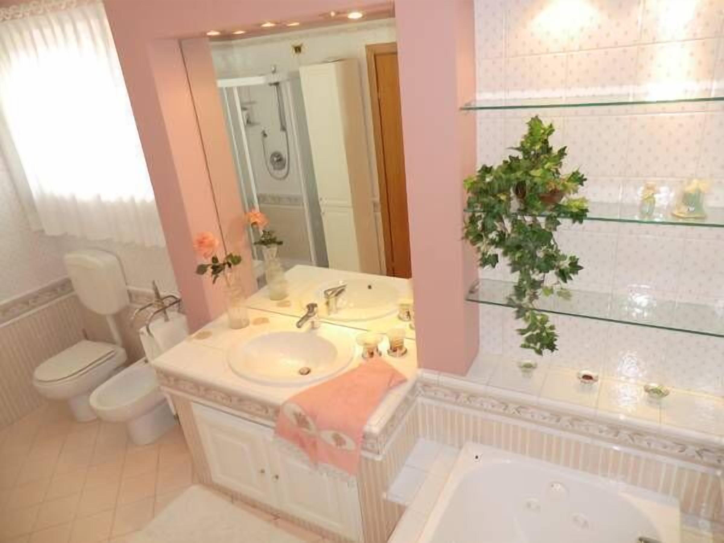 A bathroom with a bathtub, a sink, a mirror, and a toilet.