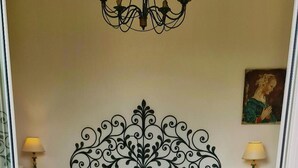 A bedroom with a bed, a chandelier, a bedside table with a lamp, and a bottle of champagne on a table. - Bed & Breakfast Isonzo (Turriaco)