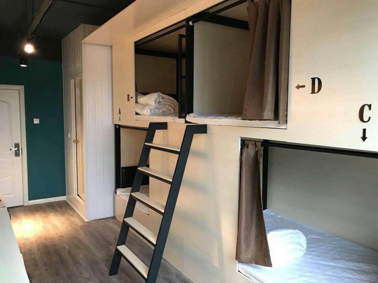 A bunk bed room with a ladder, a window with curtains, and a door.