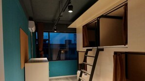Un dormitorio con literas, una escalera, un escritorio y una ventana con cortinas.