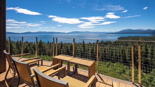 A wooden deck with chairs and a table overlooking a lake and forested mountains. - Beautiful View by Hauserman Rentals (Tahoe City)