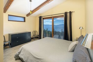 Une chambre avec un grand lit, une commode, une chaise et une vue sur la mer par la fenêtre.